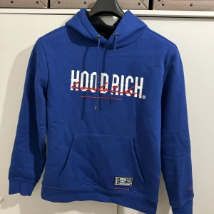 Blå hoodie från Hoodrich - Säljer en snygg blå hoodie från Hoodrich med tryck både fram och bak. Materialet är en blandning av bomull och polyester. Mycket bra skicka, som ny. Nypris:850kr