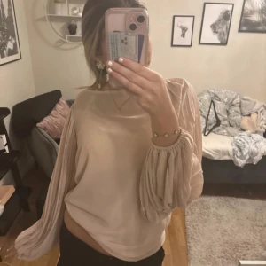 Beige blus med volangärmar - Säljer en elegant beige blus med långa volangärmar. Den kommer med ett linne under då den är lite see trough 🥰