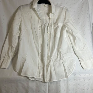 Vit skjorta från H&M - Säljer en klassisk vit skjorta från H&M i bomull. Skjortan har långa ärmar och knappar framtill samt en bröstficka. Perfekt för en stilren look.