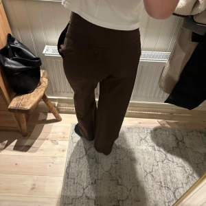 Bruna kostymbyxor - Snygga bruna kostymbyxor med en klassisk rak passform. Perfekta för en stilren look. Byxorna har en hög midja och är tillverkade i ett bekvämt material.