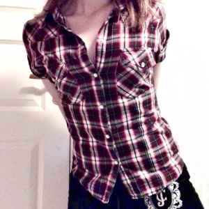 Rutig skjorta från Wear It - Säljer en snygg rutig skjorta från Wear It i rött, svart och vitt. Skjortan har korta ärmar och knappar framtill. Perfekt för en avslappnad stil med en touch av klassisk design. Passar bra till jeans eller shorts för en cool look.