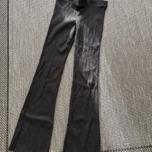 Svarta byxor från H&M Divided - Snygga svarta byxor från H&M Divided med en ribbad textur. Byxorna har en bootcut-stil med pointelle som ger en trendig look. Perfekta för att skapa en stilren outfit. • Aldrig använda •