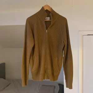 Brun stickad kofta från Jack & Jones - Brun stickad kofta från Jack & Jones. Koftan har en dragkedja framtill och ribbade detaljer. Perfekt för kyligare dagar med sin långa ärmar och bekväma passform.