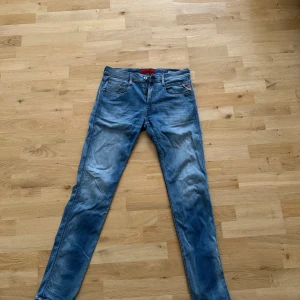Blå jeans från Replay - Snygga blå jeans från Replay med en klassisk femficksdesign och knappgylf. De har en lätt tvättad look och är perfekta för en avslappnad stil. Märkesdetaljer syns på bakfickan och insidan av linningen. Dessa har använts säkert 5 gånger bara under sommaren sen har dem blivit hängande storlek 32/34