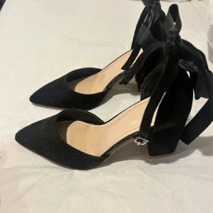 Klackar - Jättefina svarta klackar, endast använda en gång så jättebra skick. De har ett spänne man sätter fast runt ankeln och en varsin rosett bak på skon.