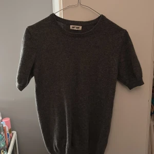 Grå kashmirtröja från Soft Goat - Säljer en stilren grå kashmirtröja från Soft Goat. Tröjan har korta ärmar och en klassisk rund halsringning. 