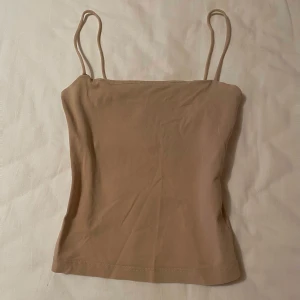 Beige topp / linne från Gina Tricot - Säljer en stilren beige linnetopp från Gina Tricot. Toppen har dubbelt lager tyg vid bröstet så man kan ha utan BH utan att något syns igenom. Storlek XS. Kontakta om du har frågor☺️