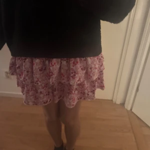 Rosa blommig volangkjol - Söt kortkjol med rosa blommigt mönster och volanger. Perfekt för en somrig look. Kjolen är bara använd 1-2 gånger