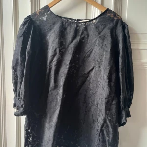 Svart blus från Pernilla Wahlgren - Elegant svart blus från Pernilla Wahlgren med blommigt mönster. Blusen har trekvartsärmar och en lätt transparent design som ger en stilfull look. Perfekt för att lyfta din outfit med en touch av elegans. Använd få tal gånger, kort vid modell och lite genomskinlig, storlek 52/54, hund finns i hemmet, skicka meddelande för mer info :) 