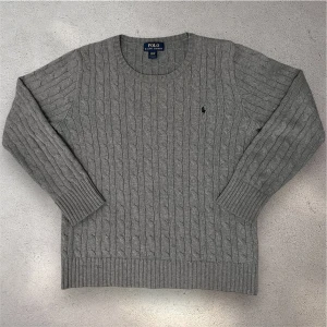Grå kabelstickad tröja från Polo Ralph Lauren - En snygg grå kabelknit från ralph lauren. Modellen är 180 cm lång och väger 65 kilo. Mycket fint skick, skriv vid frågor. Pris diskuterbart!