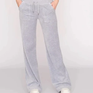 Grå mjukisbyxor med fickor - Snygga och bekväma grå mjukisbyxor med breda ben och hög midja. Byxorna har praktiska fickor fram och bak med knappar, samt en justerbar snörning i midjan. Perfekta för en avslappnad stil.