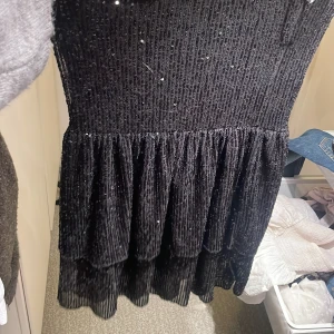 Svart glittrig klänning - VET EJ OM JAG VILL SÄLJA ISF FÖR BRA PRIS INTRESSEKOLL Snygg svart klänning med glittrande paljetter som ger en festlig look. Klänningen har en volangdetalj vid nederkanten som ger extra stil. Perfekt för en kväll ute eller en speciell tillställning. Perfekt till nyår 
