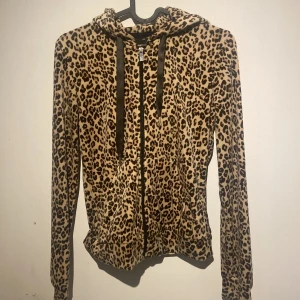 Leopardmönstrad mjukis sett från Gina Tricot - Säljer en leopardmönstrad hoodie från Gina Tricot i storlek XXS. Den har en dragkedja framtill och en huva med svarta snören. Tillkommer byxor som hör till!!! skriv privat för bilder på dem också! 