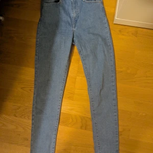Levis Blå Mile High Super Skinny Jeans - Säljer ett par blå Mile High Super Skinny jeans. De är högmidjade och har en tight passform som framhäver benen. Perfekta för en stilren look.
