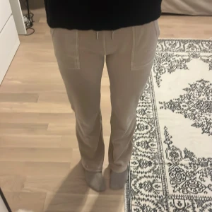 Beige mjukisbyxor från Juicy Couture - Snygga och mjuka beige mjukisbyxor från Juicy Couture med snörning i midjan och bakfickor med knappar.  Säljer då dem aldrig kommit till användning ❤️                                                        Kan gå ner i pris vid snabb affär 🫶🏼🫶🏼