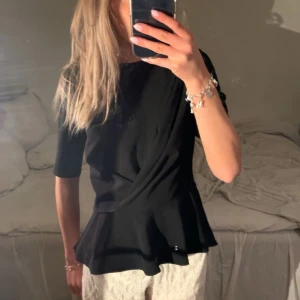 Svart trekvartsärmad topp - Snygg svart topp med volangdetaljer. Toppen är trekvartsärmad