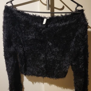 Svart fluffig tröja från NLY Trend - Säljer en svart fluffig tröja från NLY Trend. Den har en croppad design och långa ärmar, perfekt för en trendig look. Tröjan är mjuk och bekväm, idealisk för kyligare dagar. Passar bra till både jeans och kjol.
