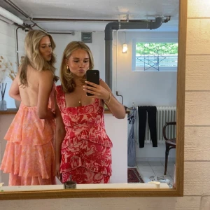 Rosa blommig klänning med volanger - Säljer en superfin rosa klänning med blommigt mönster och volanger. Klänningen har breda axelband och en lång design som ger en elegant look. Perfekt för sommarens festligheter eller bal! Köpt på asos för 1200kr! Använd bara en gång så är i väldigt bra skick! 