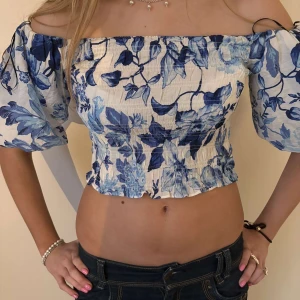 Blommig offshoulder topp - Snygg offshoulder topp med blått blommönster på vit bakgrund. Toppen är croppad och har puffiga kortärmar. Perfekt till sommarn 🥰