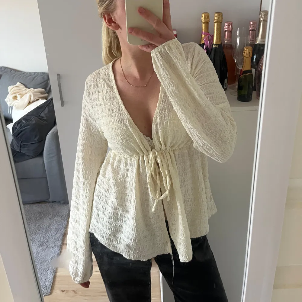 Säljer denna fina kräm vita topp frön Gina Tricot med långa armar och knyte.. Yläosat.