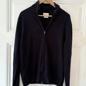 Blå merinoulltröja från These Glory Days - Säljer en stilren marinblå fullzip i merinoull från These Glory Days i M. Sparsamt använd, bra skick. Passar runt 175-185