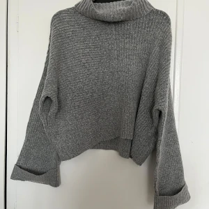 Grå stickad polotröja från New Yorker  - Mysig grå stickad polotröja från New Yorker med en avslappnad passform. Tröjan har långa ärmar och en bred polokrage som ger extra värme. Perfekt för kyliga dagar. 🥰