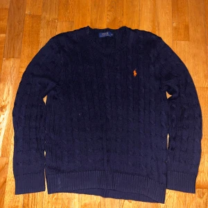 Mörkblå stickad tröja från Ralph Lauren - Säljer en snygg mörkblå stickad tröja från Ralph Lauren. Tröjan har ett flätat mönster och långa ärmar, perfekt för kyligare dagar. Säljer pågrund av att den inte kommer till används. Skriv om ni har några funderingar eller frågor om tröjan.😊