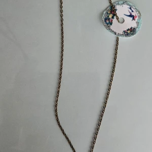 Halsband med hjärtberlock - Charmigt halsband med en antikfärgad kedja.  Fint hjärta med en grön detalj i mitten. Perfekt för att ge en personlig touch till din stil.