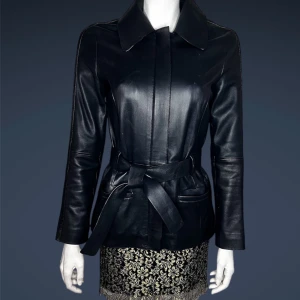 Massimo Dutti- Svart nappa skinnjacka med bälte - Snygg svart nappa skinnjacka med bälte i midjan för en stilren look. Jackan har långa ärmar och en klassisk krage. Perfekt för att ge en edgy touch till din outfit.