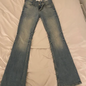 Blå bootcut jeans från Bershka - Snygga bootcut low waist bershka jeans med dubbel knapp. Säljer pga att det inte kommer till användning och är i mycket mycket bra skick då den är använd 1-3 gånger med inga defekter. Jeansen är ganska stretchiga och bra i längden.