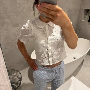 Vit blus från Paris Atelier & Other Stories - Säljer en söt vit blus från Paris Atelier & Other Stories. Blusen har korta puffärmar och ett vackert broderat mönster. Den är knäppt framtill och har en klassisk krage. Perfekt för en somrig look! 🌸