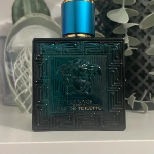 Versace Eros Eau de Toilette - Letar efter något att byta mot Versace Eros Eau de Toilette, 50 ml. Flaskan har en djupblå färg med ett elegant mönster och ett blått lock. Den är prydd med Versaces ikoniska Medusa-motiv. Perfekt för den som vill ha en doft med karaktär och stil. Den är knappt använd som ni ser på bilden. 