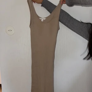 Beige ribbad klänning - Snygg beige ribbad klänning med ärmlös design och v-ringad hals. Perfekt för en stilren och enkel look.