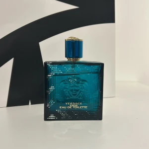 Versace Eros Eau de Toilette - Versace Eros Eau de Toilette i en elegant blå flaska med guldlock. Flaskan har ett stilrent mönster och pryds av Versaces ikoniska Medusa-motiv. Perfekt för den som vill ha en doft med karaktär och stil. Den är som ny har använt den nån gång men nästan hell ful 