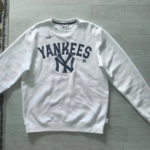 Yankees sweatshirt  Nike - Säljer en vit sweatshirt från Nike med Yankees-logga i blått. Tröjan har långa ärmar och en rund halsringning. Perfekt för sportiga tillfällen eller som en casual vardagströja.