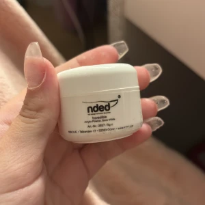 Nded akrylpulver - Nded akrylpulver i en vit burk. Perfekt för att skapa hållbara och starka naglar. Burken har en varningstext och symboler för säker användning. Färgen heter snow white lite kvar i burken.