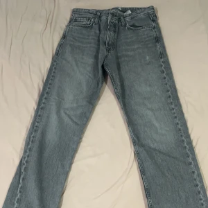 Grå jeans - Säljer ett par grå jeansbyxor med loose fit från jack and jones. Byxorna har en klassisk design med dragkedja och knappar. Perfekta för en avslappnad stil. Nypris 600kr. Använda max 10 gånger. I nyskick.