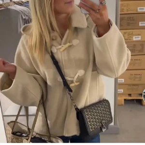 Beige kappa från Zara - Snygg beige duffeljacka med träknappar och huva. Jackan har en avslappnad passform och är perfekt för kyligare dagar. Den har långa ärmar och en klassisk design som aldrig går ur stil🤩💕 Den är ifrån Zara barn men passar S/XS😍😍Går inte att hitta längre