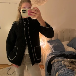 Svart jacka från Women'secret - Snygg svart jacka från Women'secret med vita sömmar och stora fickor fram. Perfekt för en stilren look. Jackan har långa ärmar och en bekväm passform.