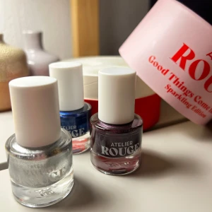 3 Nagellack från Atelier Rouge - Set med tre nagellack från Atelier Rouge i en snygg förpackning. En silvrig, röd/lila och en mörkblå. Alla glittriga. Hör av vid frågor. Nya, endast testade på en nagel en gång för att se färg. 