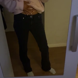 Svarta/gråa  jeans - Snygga svarta jeans med en tight passform. De har en klassisk design med knappar och dragkedja framtill. Perfekta för en stilren look.