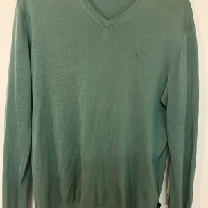 Grön tröja från Tiger of Sweden - Snygg grön tröja från Tiger of Sweden i en mjuk blandning av siden och bomull. Tröjan har en v-ringad hals och långa ärmar, perfekt för en stilren look.