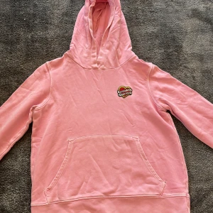 Rosa hoodie från Zadig & Voltaire - Säljer en rosa hoodie från Zadig & Voltaire med en cool broderad hjärtdetalj på bröstet. Den har en klassisk känguruficka och en bekväm huva. Perfekt för en avslappnad stil.