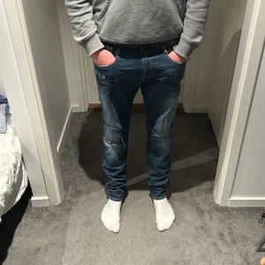 Replay Jeans - Tja säljer ett par jeans ifrån Replay med slitningar modellen på jeansen är Anbass och storleken är 30/30. 