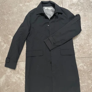 Svart rock från HOPE  - Elegant svart rock från HOPE med klassisk krage och knappar framtill. Rocken har långa ärmar och två fickor. Perfekt för en stilren vår/höstlook .