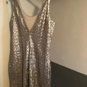 Silver paljettklänning från Gina Tricot - Snygg silverfärgad klänning från Gina Tricot täckt med glittrande paljetter. Den är ärmlös och har en figurnära passform, perfekt för en festlig kväll.