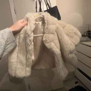 Beige pälsjacka - Säljer en fluffig och stilren beige pälsjacka med långärmad design. Perfekt för att hålla sig varm och trendig under kyliga dagar. Jackan har en klassisk look som passar till många olika outfits. Jätte söt till ett vanligt linne som en liten extra detalj på💞
