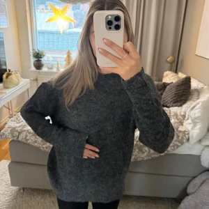 Mörkgrå stickad tröja - Mysig mörkgrå stickad tröja med långärmad design. Perfekt för kyliga dagar med en bekväm och avslappnad passform. Ett måste i garderoben för höst och vinter!