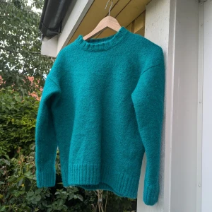 Grön stickad tröja från Zara - Säljer en superfin stickad tröja från Zara. Den är perfekt för kyliga dagar med sin mysiga och varma känsla. Tröjan har långa ärmar och ribbade kanter vid ärmslut och nederkant.Det finns ett hål som behöver lagas, och tröjan har krympt i tvätten.