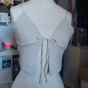 Söt Topp - En söt beige topp, med knything på bröstet och justerbaraaxelband. Köppt på H&M, har ej haft den på mig många gånger. Storlek M